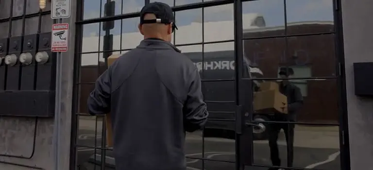 Man delivering packages to a building with large glass windows