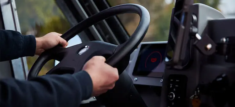 Closeup of driver's hands on the steering wheel of a Workhorse electric step van 