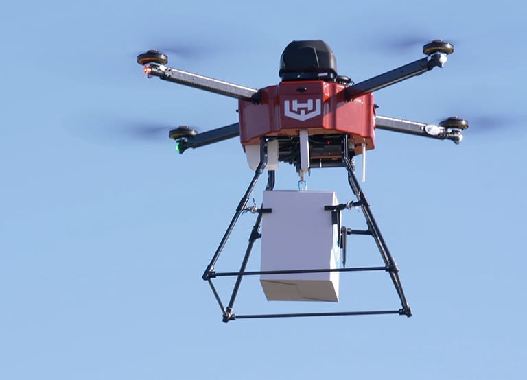 Delivery drone in flight in front of blue sky