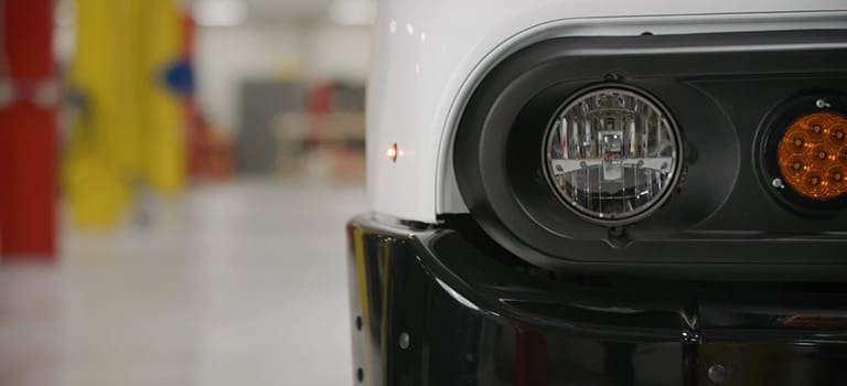 Closeup of the headlight of a white electric delivery step van