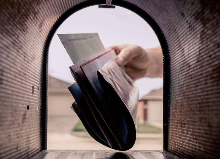 Photo From Inside A Mailbox Shows Hand Placing Letters Inside.